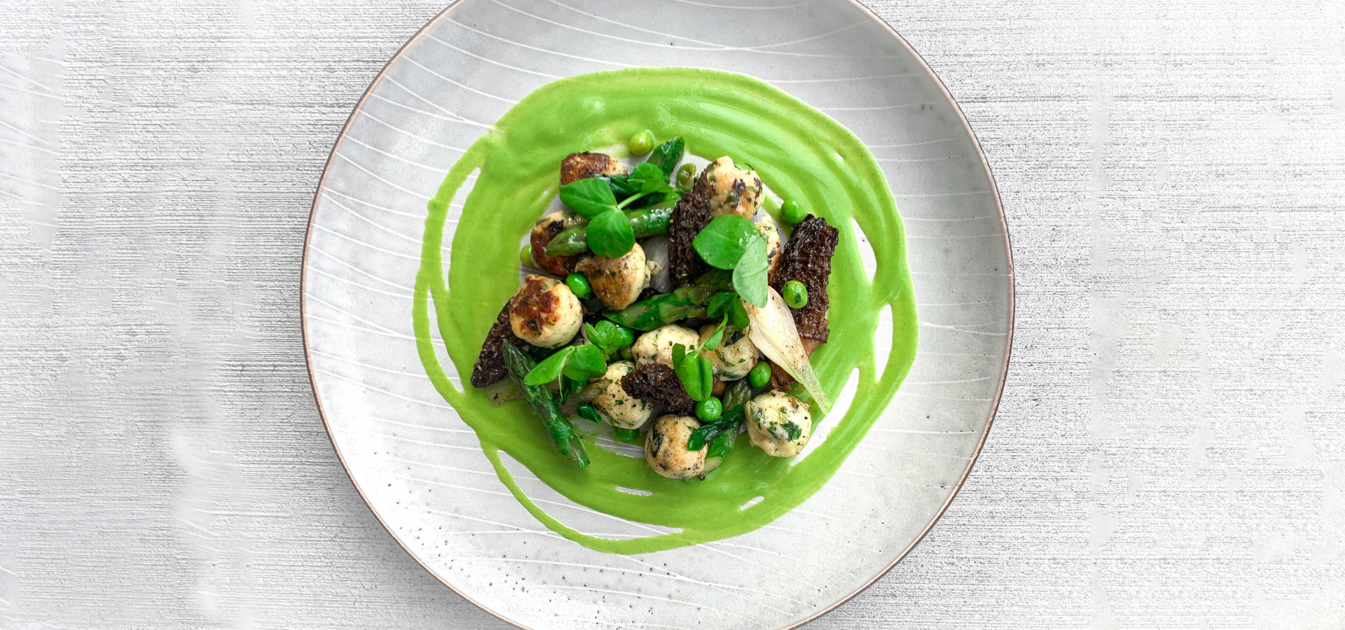 Easter dish showing ricotta cheese dumplings with mushrooms, peas, asparagus in green sauce