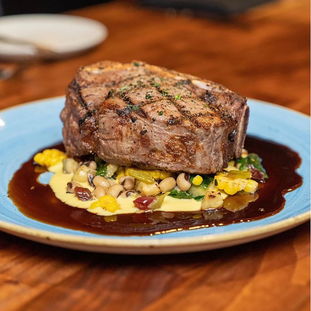 A hyplains heritage farms bone-in filet with vegetables.