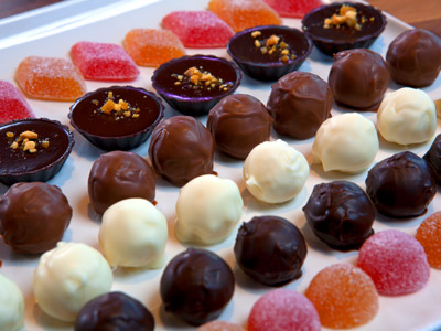 Milk, white, and dark chocolate balls and brightly colored fruit gels in rows on a white cloth.