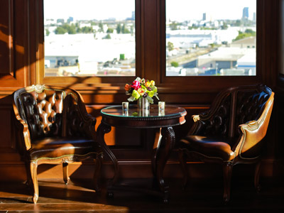 A wooden round table set with flowers and candles, in between two leather chairs.