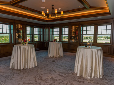 Three standing tables decorated with white tablecloths and floral centerpieces.