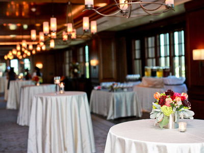 4 standup tables decorated with candles and floral centerpieces.