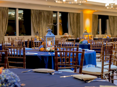 The Great Room set up with round tables and lantern and tiny pumpkin centerpieces.