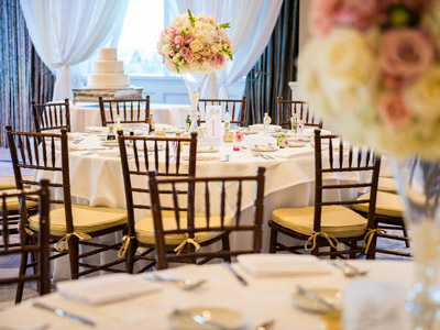 A round table set with glassware and flatware, pink and white flowers, and candles.