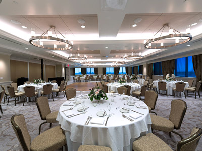 The Great Room's dining tables and flowers, a dance floor, DJ stand, and chandeliers.