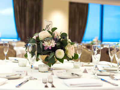 Close up of a table with candles and a plant centerpiece.