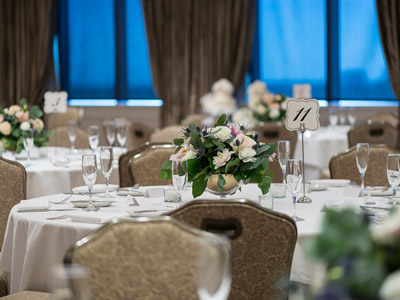 Close up of a table with a table number, candles, and a plant centerpiece.