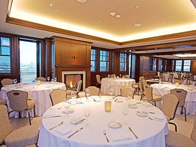 The Hospitality Suite dining area, with tables set for dinner and a lit fireplace.