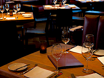 A close look of a leather booth with a wooden table and menus.