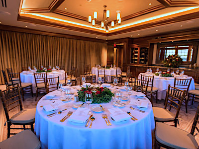 The Study wtih round tables set with Christmas decor, wooden chairs, and built in wine cabinets.