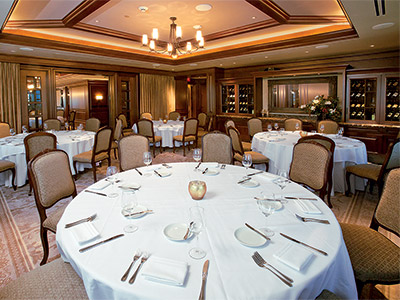 The Study set up with with round tables, tan seats, built-in wine cabinets, and a mirror.